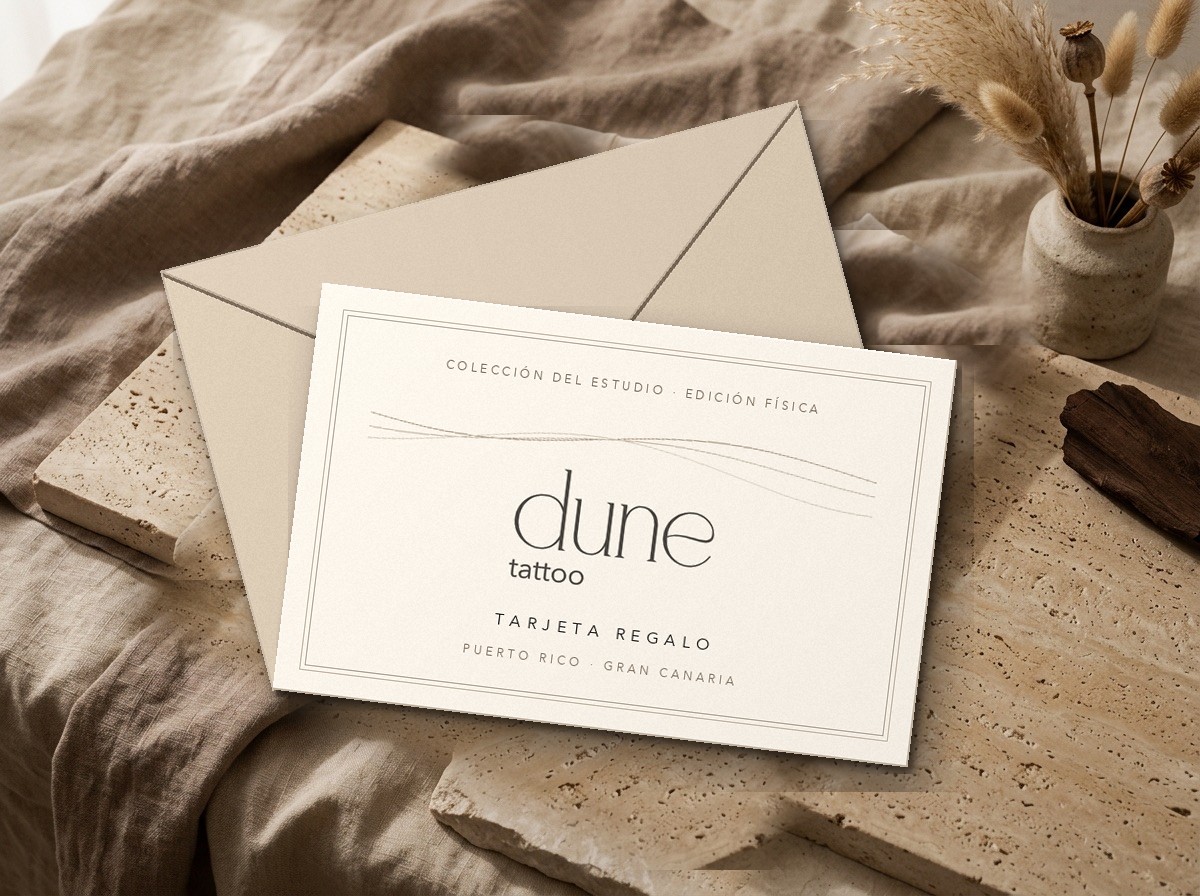 Tarjeta regalo física de Dune Tattoo Studio en papel algodón marfil y sobre arena sobre piedra travertino